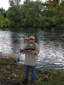 Zack Walburn next to a river, holding a fish