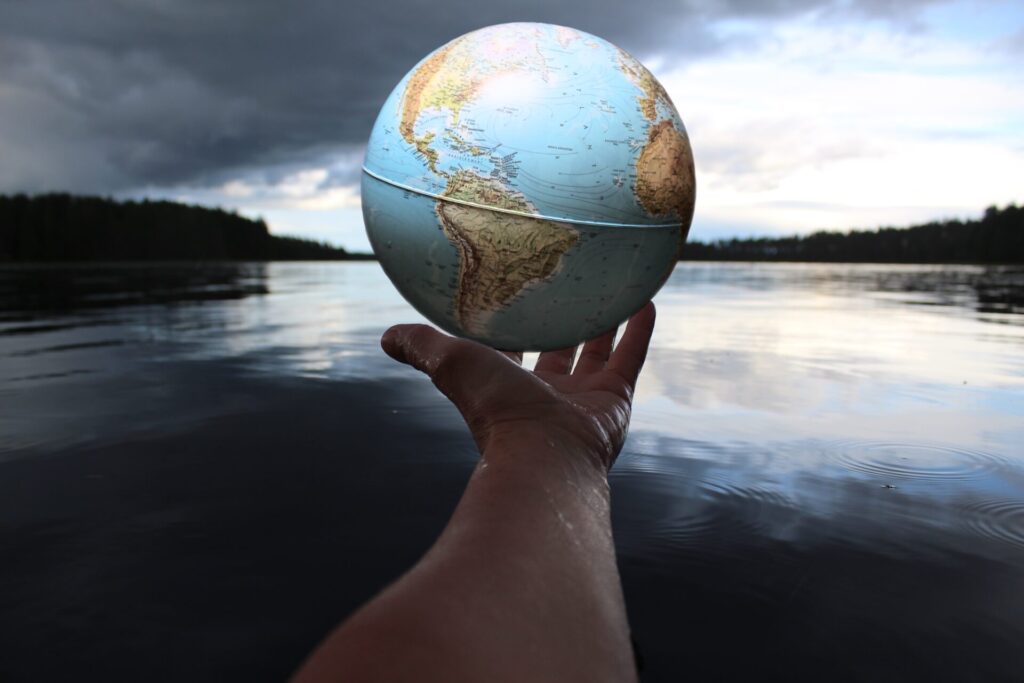 Photo shows a person's hand holding a small earth globe